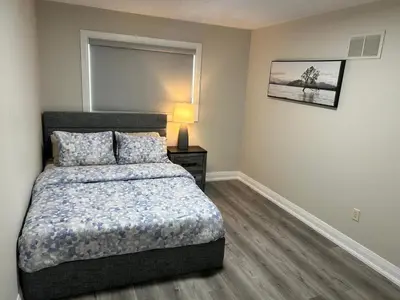 a bedroom with a bed and a lamp on a table at Treasure Haven Near Tourism Barrie in Barrie