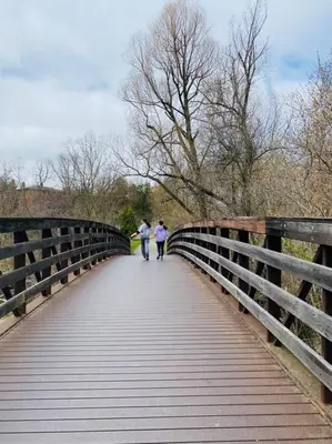 two people walking across a bridge at Serene Don River Nature gateway- 2BR suite, Private Patio, Free Parking in Toronto