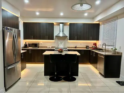 a kitchen with wooden cabinets and a island with a refrigerator at Beautiful Family Suites - Master Bedroom in Niagara Falls