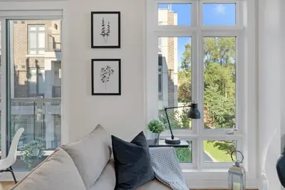 a living room with a couch and a window at Designer Yorkdale 2BR Townhouse, Private Patio, Parking in Toronto