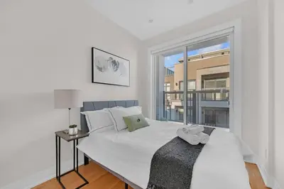 a bedroom with a large white bed and a window at Designer Yorkdale 2BR Townhouse, Private Patio, Parking in Toronto