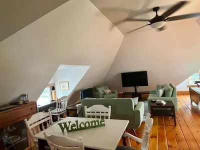 a living room with a ceiling fan and a table and chairs at The Lakeview Loft in Port Colborne