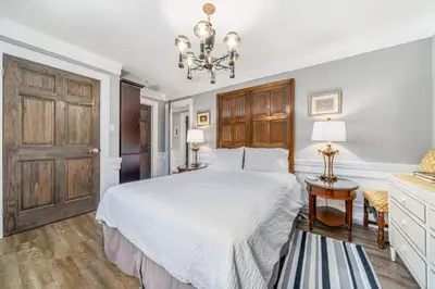 a bedroom with a white bed and a chandelier at Gate House Comfort plus own lake access, dock, 4 mins to beach in West Lake