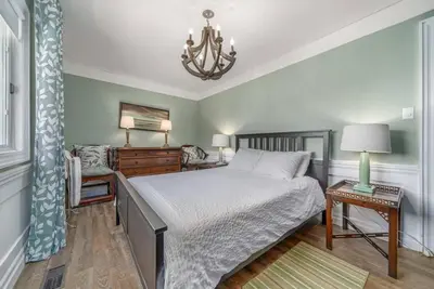 a bedroom with a bed and a chandelier at Gate House Comfort plus own lake access, dock, 4 mins to beach in West Lake