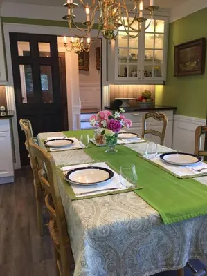 a dining room table with a green table cloth and plates and flowers at Gate House Comfort plus own lake access, dock, 4 mins to beach in West Lake