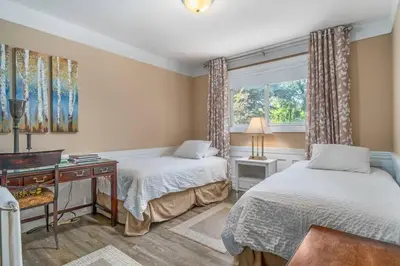a bedroom with two beds and a desk and a window at Gate House Comfort plus own lake access, dock, 4 mins to beach in West Lake