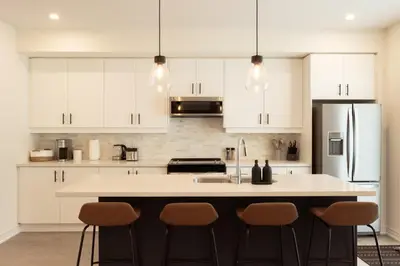 a kitchen with white cabinets and a kitchen island with stools at Spotless 4 bed and 3 bath with Wi-Fi and 1hr to Niagara in Hamilton