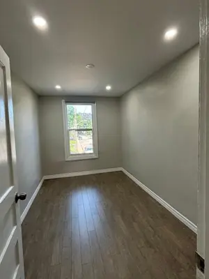 an empty living room with a window and wooden floors at H men's dormitory in Hamilton