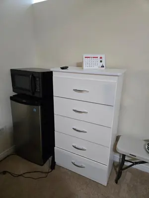 a white dresser with a microwave and a desk at Mimis lodge in Brampton