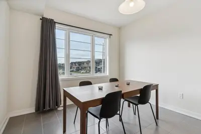 a dining room with a table and chairs and a window at A Brand New 4BR Townhouse in Thorold Retreat in Thorold