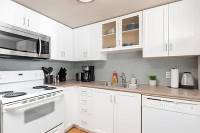 a white kitchen with a stove and a sink at Comfy Liberty Village Home 1BD Steps from King St in Toronto