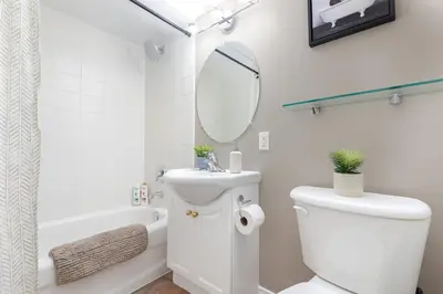 a white bathroom with a toilet and a mirror at Comfy Liberty Village Home 1BD Steps from King St in Toronto
