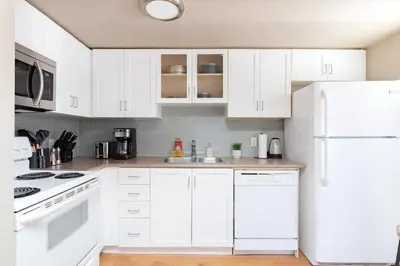 a kitchen with white cabinets and a white refrigerator at Comfy Liberty Village Home 1BD Steps from King St in Toronto
