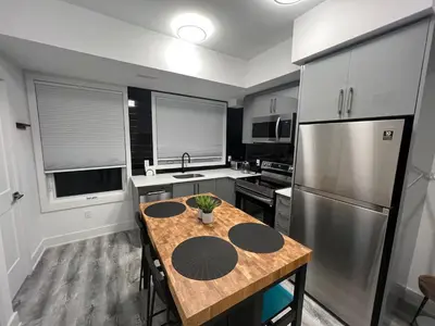 a kitchen with a wooden table and a stainless steel refrigerator at 2 Bed Town ideal for a fun-filled family vacation in Niagara Falls