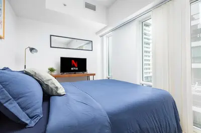 a bedroom with a blue bed and a tv at Modern Micro Studio in Heart of Downtown in Toronto