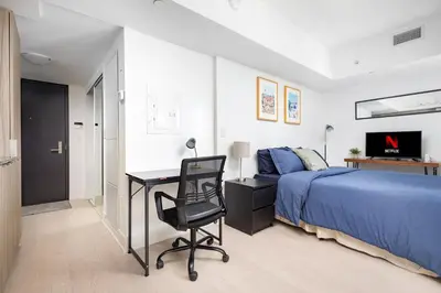 a bedroom with a bed and a desk and a chair at Modern Micro Studio in Heart of Downtown in Toronto