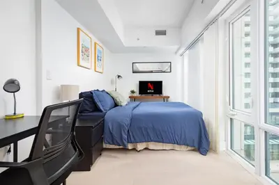 a bedroom with a bed and a desk with a laptop at Modern Micro Studio in Heart of Downtown in Toronto