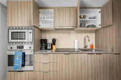a kitchen with wooden cabinets and a stove and a sink at Modern Micro Studio in Heart of Downtown in Toronto