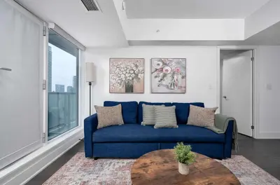 a blue couch in a living room with a table at Modern 1BR Condo by Yorkville w Sofa Bed Sleeps 3 in Toronto