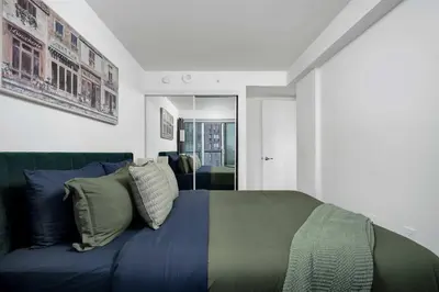 a bedroom with a blue bed and a couch at Modern 1BR Condo by Yorkville w Sofa Bed Sleeps 3 in Toronto