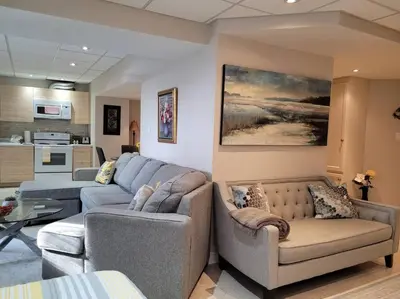 a living room with two couches and a kitchen at Cozy and comfy Studio Apartment in Richmond Hill