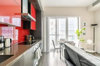 a kitchen with red and black cabinets and a table at Modern Suite w City Views - Downtown in Toronto