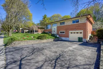 a brick house with a driveway and a garage at Bright & Modern 1 bedroom unit! in Guelph