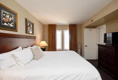 a bedroom with a white bed and a television at Jacuzzi Suite with King bed, full kitchen in Shanty Bay