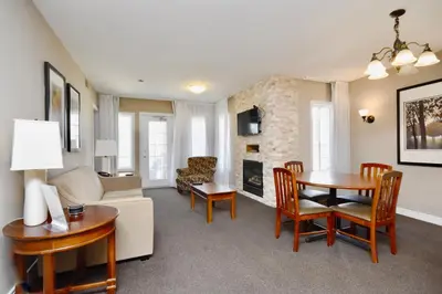 a living room with a couch and a table and a fireplace at Jacuzzi Suite with King bed, full kitchen in Shanty Bay