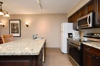 a kitchen with a sink and a refrigerator at Jacuzzi Suite with King bed, full kitchen in Shanty Bay