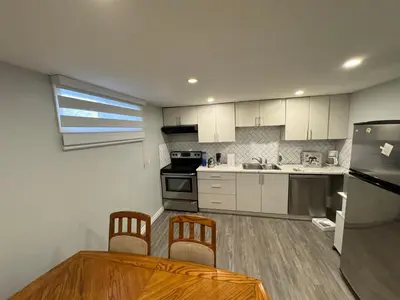 a kitchen with white cabinets and a table and chairs at 1 bedroom cozy apartment in Kitchener