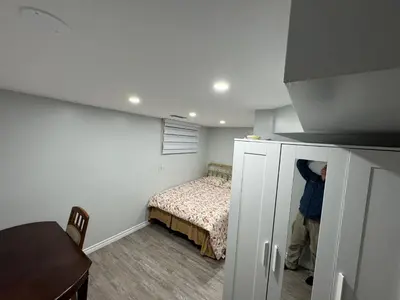 a man standing in a bedroom with a bed at 1 bedroom cozy apartment in Kitchener
