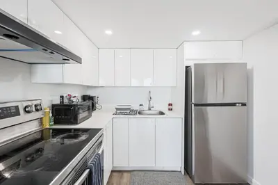 a kitchen with white cabinets and a stainless steel refrigerator at Exquisite 2-Bdrm Basement Suite with FREE Parking in Bradford