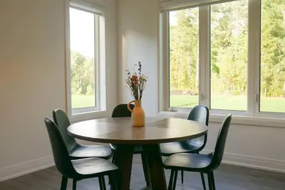 a dining room table with chairs and a vase with flowers at Spacious 3 Bdrm Retreat, Muskoka Room & Fireplace in Bracebridge