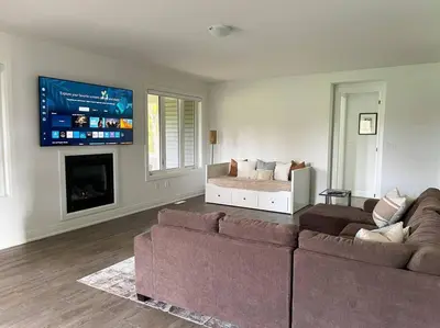 a living room with a couch and a tv at Spacious 3 Bdrm Retreat, Muskoka Room & Fireplace in Bracebridge
