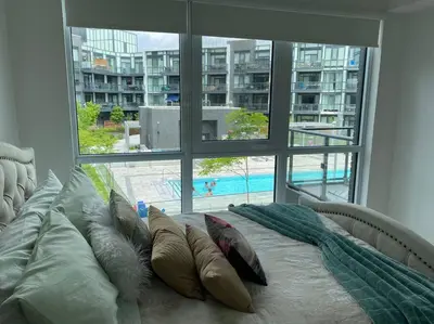 a bedroom with a bed with pillows and a large window at Beautiful Condo, 2 Bedrooms and a Den in Friday Harbour Resort! in Innisfil