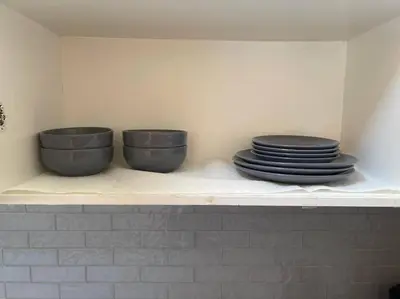 three bowls and plates on a shelf in a kitchen at Quaint and Cozy Haven in Toronto