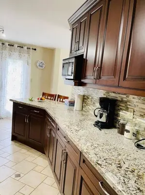 a kitchen with wooden cabinets and a marble counter top at Three bedroom house in Mississauga