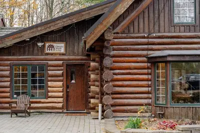 a log cabin with a door and a chair outside at Forest Hideaway in Hespeler
