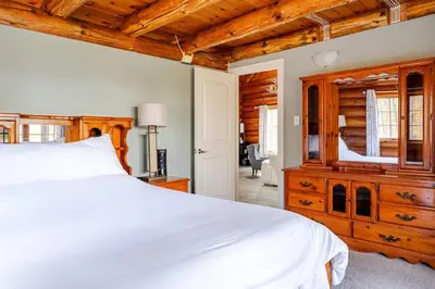 a bedroom with a white bed and a wooden dresser at Forest Hideaway in Hespeler