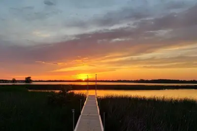 a wooden pier with the sunset in the background at Westlake waterfront, hot tub, dock,4 mins to beach in West Lake