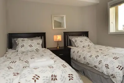 a bedroom with two beds and a table with a lamp at Boardwalk Homes - Executive Townhomes in Kitchener