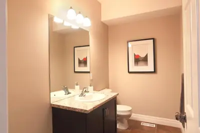 a bathroom with a sink and a toilet and a mirror at Boardwalk Homes - Executive Townhomes in Kitchener