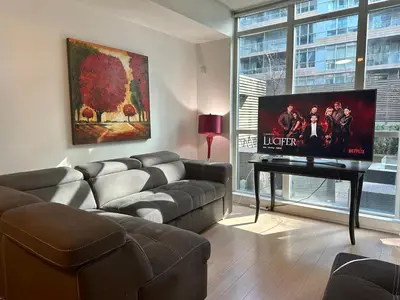 a living room with a couch and a flat screen tv at 1Bdrm plus den with 2 real beds plus sofabed & Terrace & parking in Toronto