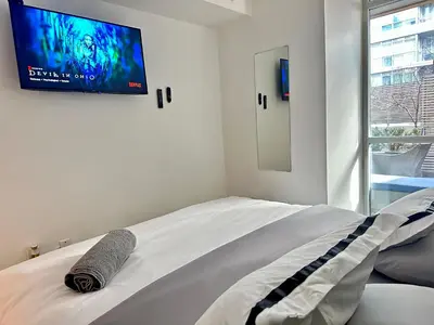 a bedroom with a bed with a flat screen tv on the wall at 1Bdrm plus den with 2 real beds plus sofabed & Terrace & parking in Toronto