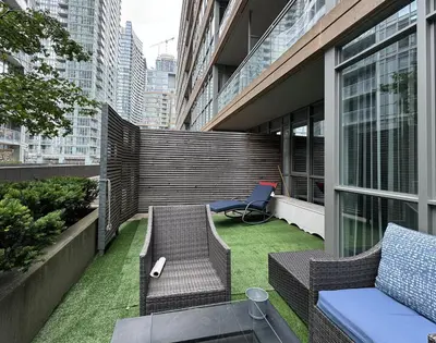 a small patio with chairs and grass on a building at 1Bdrm plus den with 2 real beds plus sofabed & Terrace & parking in Toronto