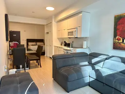 a living room with a blue couch and a kitchen at 1Bdrm plus den with 2 real beds plus sofabed & Terrace & parking in Toronto