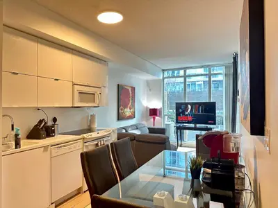 a kitchen and a living room with a table at 1Bdrm plus den with 2 real beds plus sofabed & Terrace & parking in Toronto