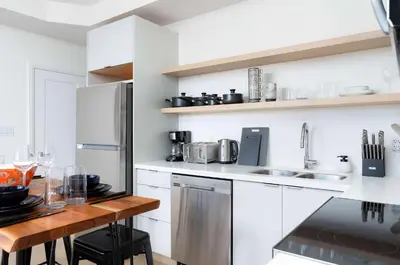 a kitchen with white appliances and a wooden table at Large Victorian Sleeps 6 by UofT in Toronto