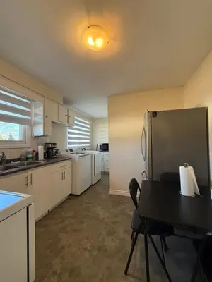 a kitchen with a refrigerator and a table with a chair at Niagra Luxury Home in Thorold